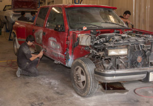 Two Auto Body Repair students work on an old truck.