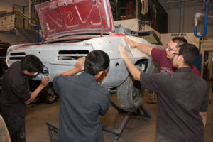 Four students prepare a car for painting.