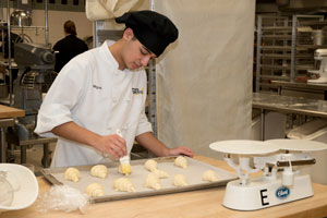 Baking student preparing crescent rolls on a tray.