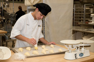Baking student preparing crescent rolls on a tray.
