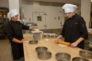 Two RMCTC students roll and weigh pastry dough.