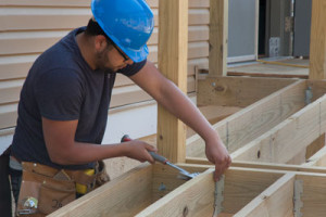 Carpentry student nails a floor joist into position on entrance ramp. 