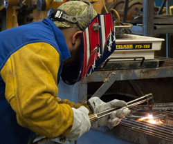 A student uses a torch to cut steel in Welding class.