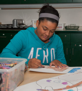 A student prepares art for a classroom bulletin board.