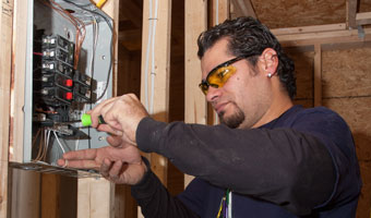 An adult Electrical Technology student wires a circuit breaker in a service panel.