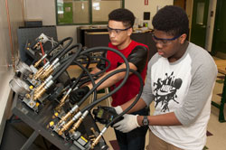 Two engineering students check the pressure of a hydraulic system.