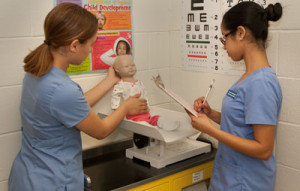 Students weigh a baby doll on a scale.