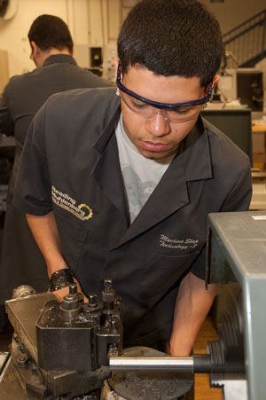 A student operates a lathe in the Machine Shop program.