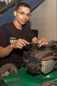 A student performs maintenance on a lawn mower.