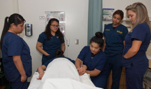 One student demonstrates massage techniques as fellow students observe.