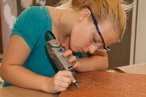 A Painting & Decorating etching a design into a wood surface as part of a project.