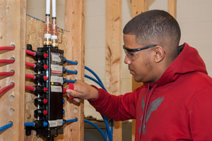A student in the Plumbing and Heating program works on a PEX manifold.