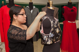 A student adjusts a garment on a mannequin.