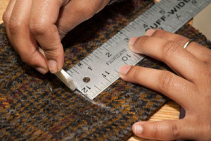 A close-up of hands marking fabric with chalk.