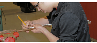 Student measures copper tubing while preparing to cut it to length.