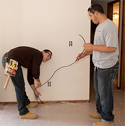 Two Electrical Technology students run coaxial cable during a house renovation project.