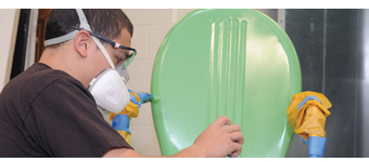 A student spray paints a chair in Painting and Decorating class.