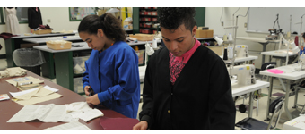 Two students work at a table in sewing class.