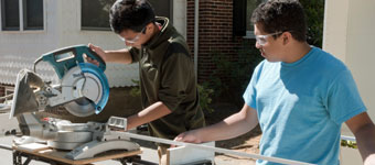 Carpentry students use a miter saw on a home renovation project in the community.