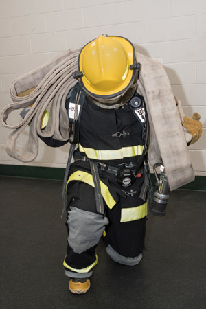 A PSS student in full firefighting gear with hose