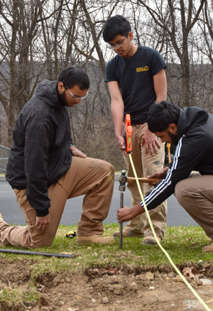 Students measure and position a stake in preparation for excavation.