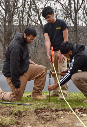 Students measure and position a stake in preparation for excavation.