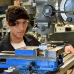 A 3D Manufacturing student operates a milling machine.
