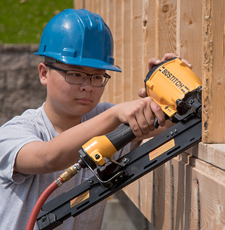 Carpentry student uses a nail gun.