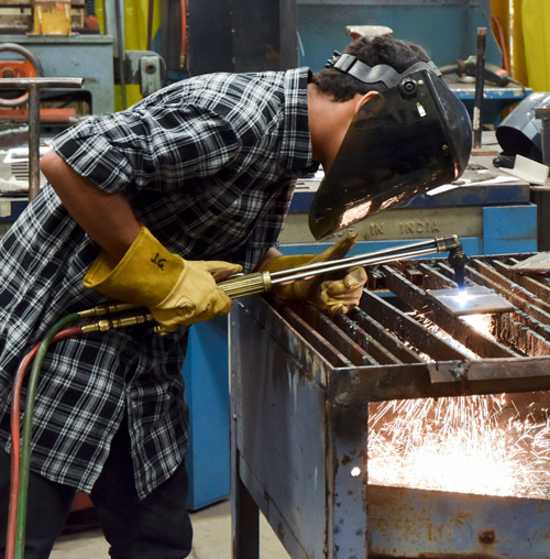 Welding student uses a torch to cut metal