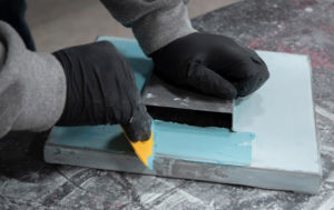 A student in Auto Body Repair applies filler to a piece of metal.