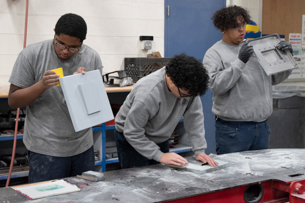 Students in Auto Body Repair sand pieces in preparation for painting.