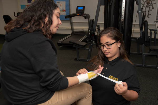 A Sports Medicine student practices wrapping a wrist injury.