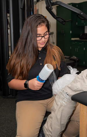 A Sports Medicine student demonstrates how to apply ice to a knee injury.