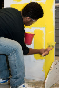 A student paints a door in Painting & Decorating class.