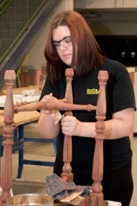 A student in the Painting & Decorating program prepares a piece of furniture for refinishing.