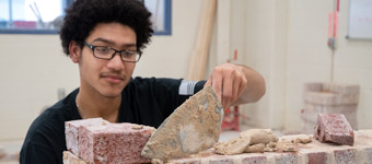 A Bricklaying student builds a wall.